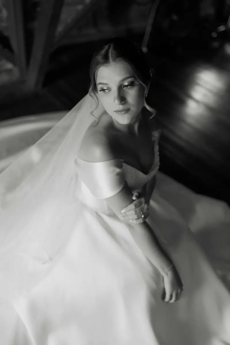 A bride looking towards the camera in soft black and white light