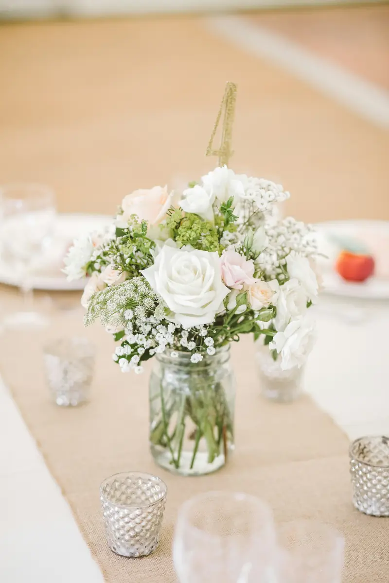 White roses and greenery arranged in glass vases