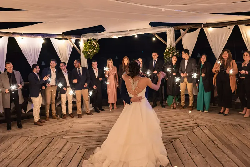A wedding couple dancing surrounded by guests holding sparklers