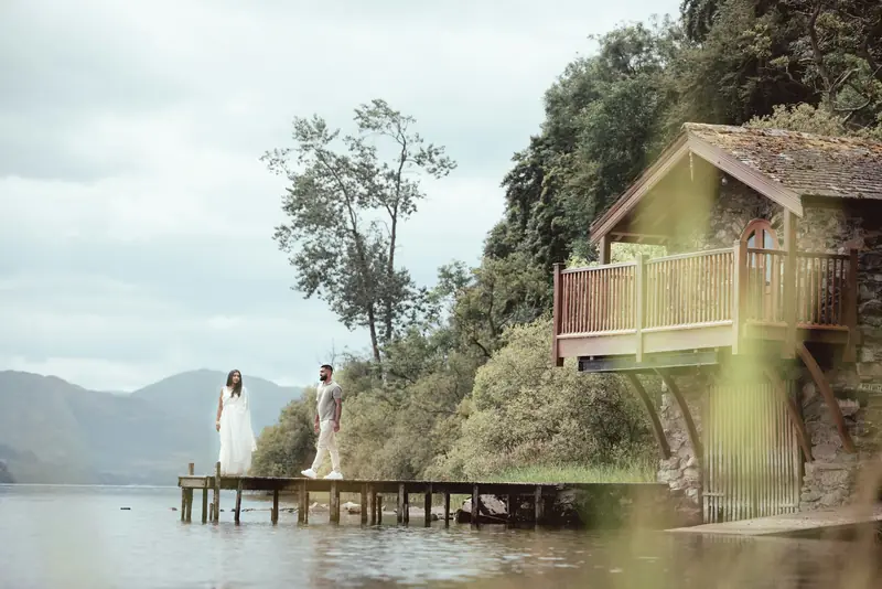 Bride and groom standing on a wooden jetty in the Lake District