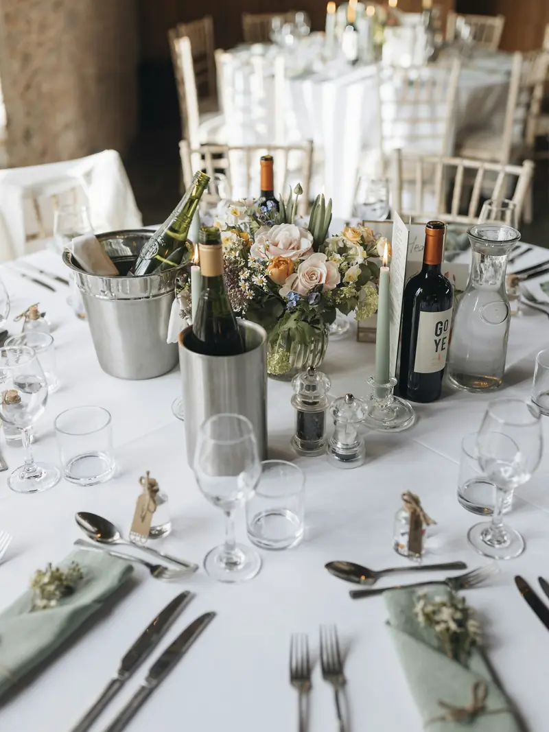 Wedding breakfast table with flowers, wine and place settings