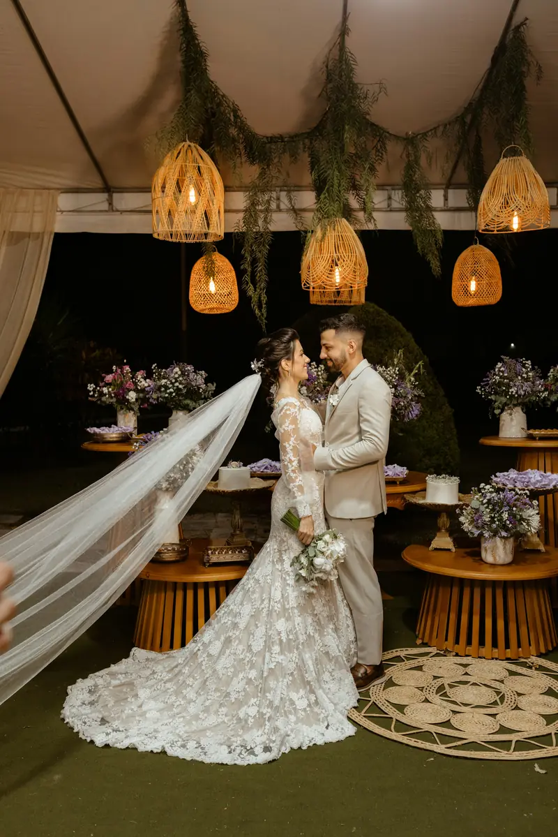 A bride and groom embracing beneath hanging woven lamps